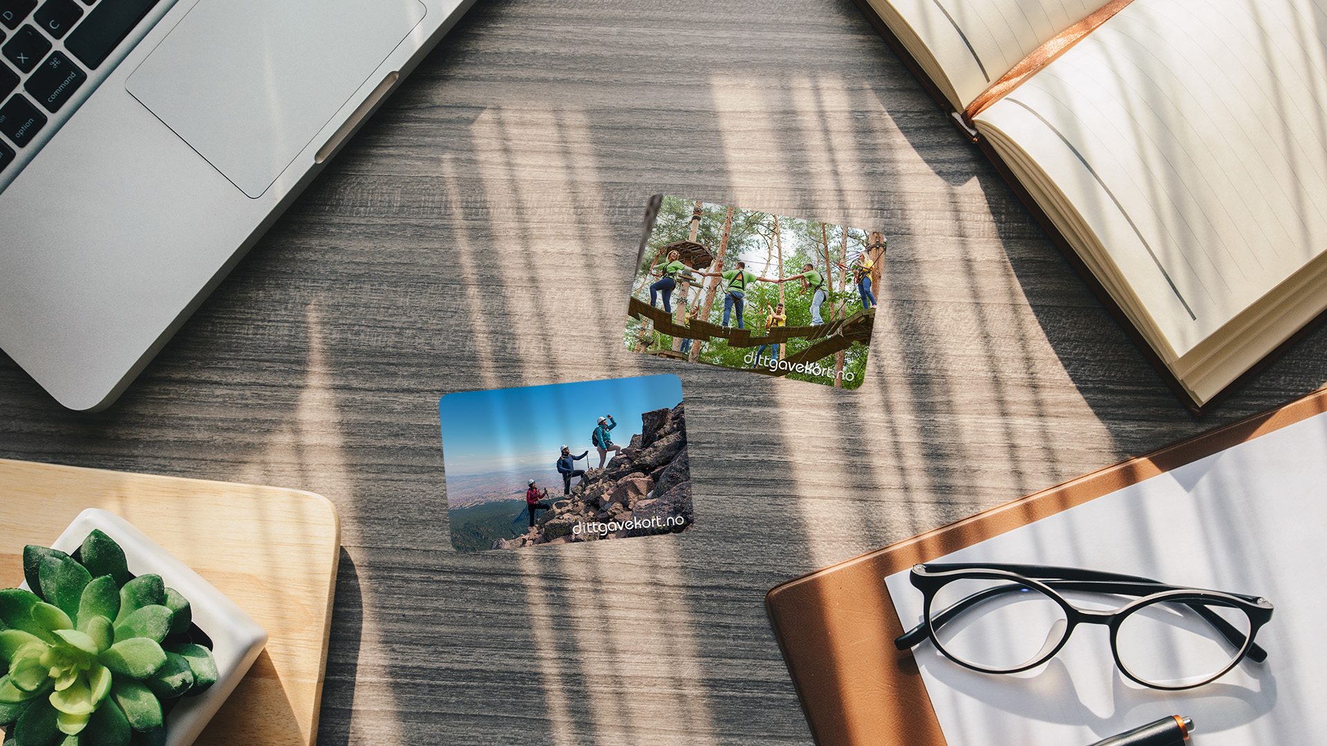 To gavekort som tar i bruk egne bilder på et skrivebord med laptop, notatbøker, lesebriller og en plante