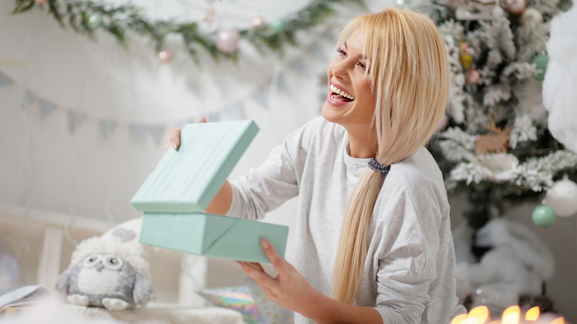 Dame som åpner gave ved siden av juletreet