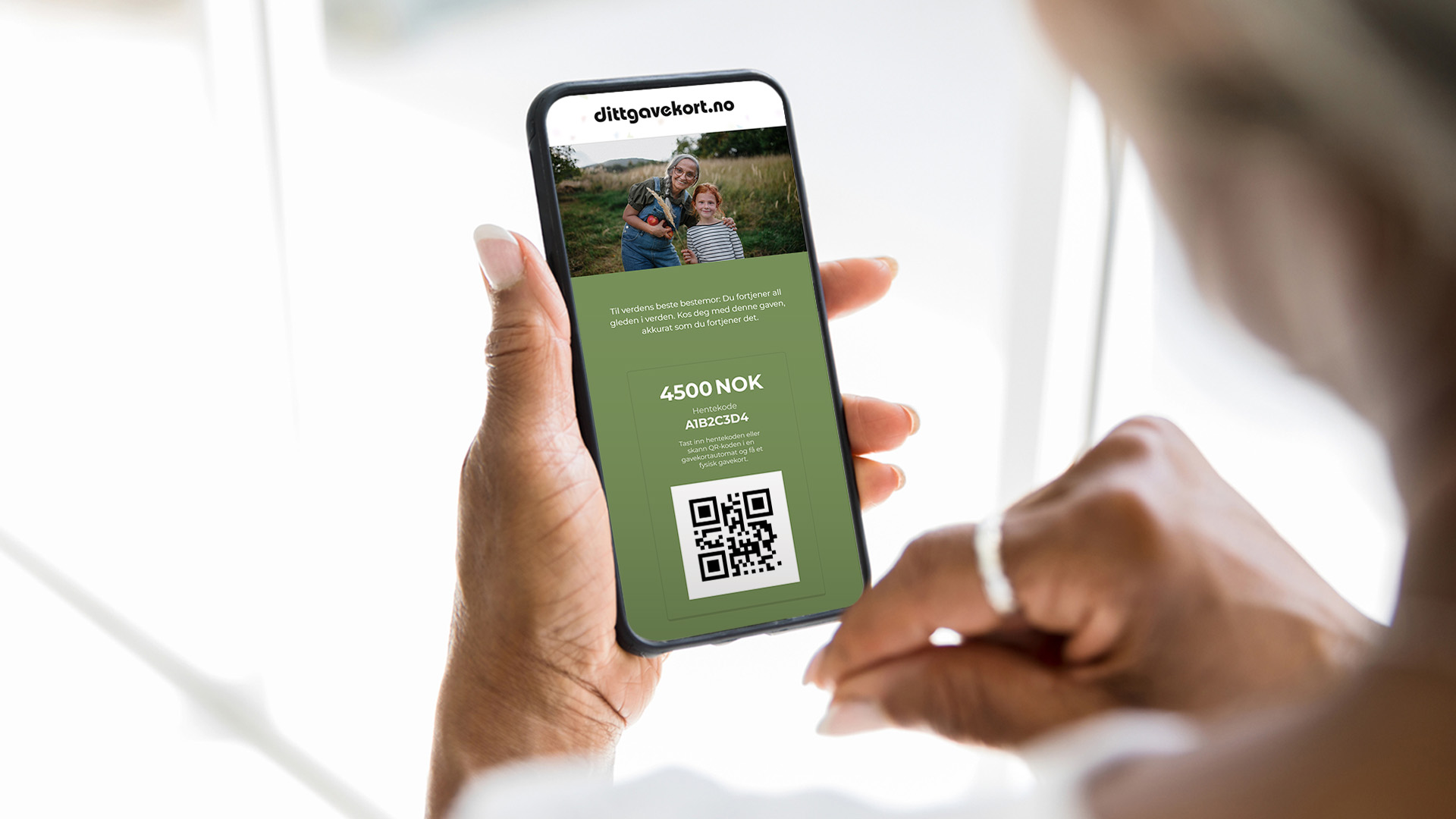 eldre dame som holder en mobiltelefon med dittgavekort på skjermen