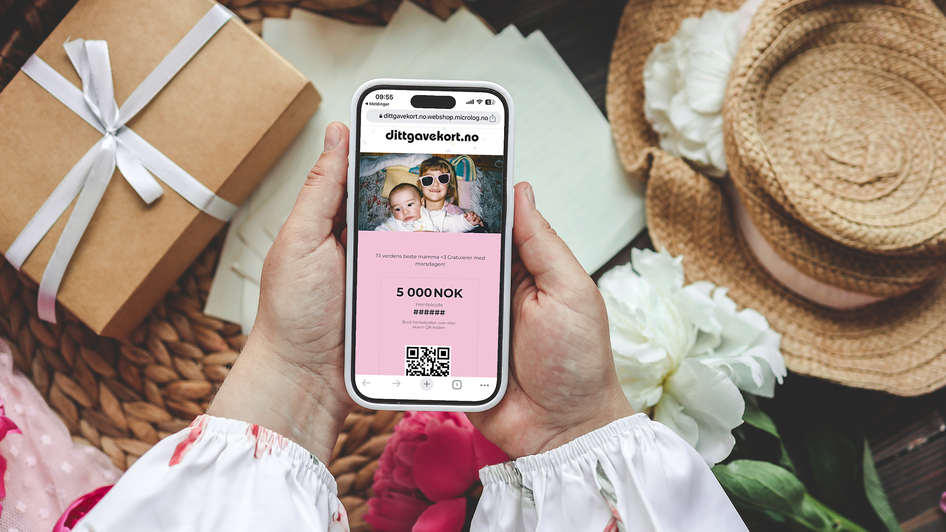 Bilde av an dame som holder smarttelefon med dittgavekort på nettleser omringet av blomster, gavepakke og stråhatt