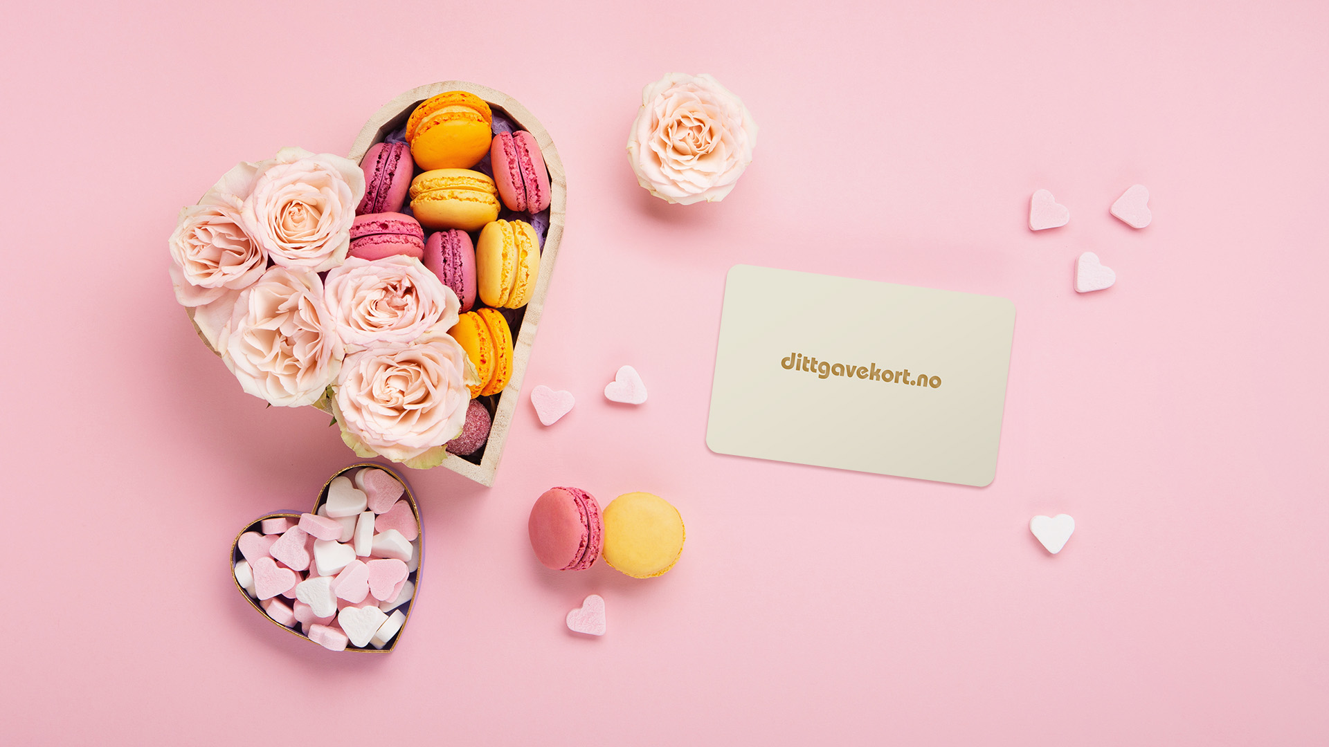 Dittgavekort med hjerteformet boks med makroner og roser og hjerteformet godteri på rosa bakgrunn