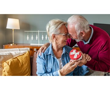 Et eldre par som holder en hjerteformet gaveeske
